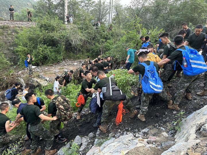8月2日，Z180次受困列车的旅客在武警北京总队机动第三支队官兵的帮助下徒步前往转运客车（手机照片）。