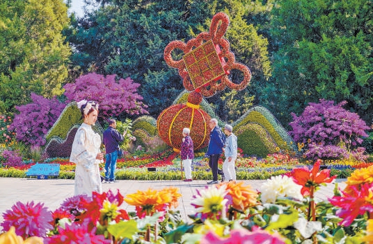 天坛公园北门内“山河结彩”立体花坛已布置完成，游客纷纷驻足拍照。