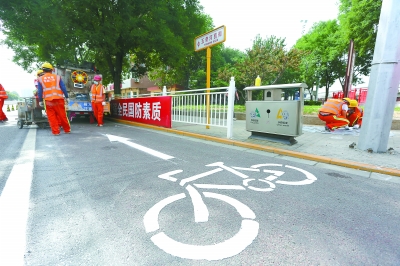 施工人员在施划自行车道图标。 施工人员在施划自行车道图标。