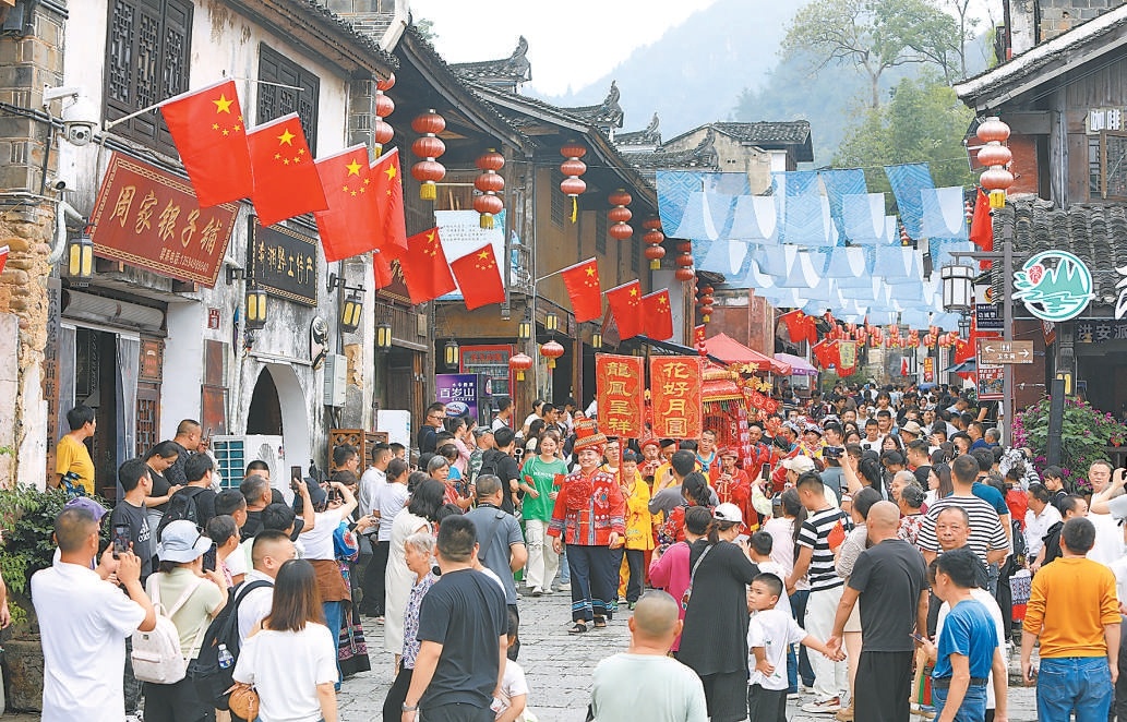 双节期间，游客在重庆市秀山土家族苗族自治县洪安古镇老街观看土家婚俗展演。2025年国庆与中秋“双节”叠加，各地丰富文旅供给，促进假日文化和旅游消费。