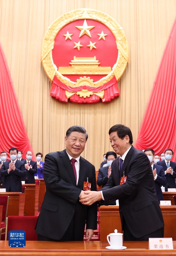 3月10日，十四届全国人大一次会议在北京人民大会堂举行第三次全体会议。习近平全票当选中华人民共和国主席、中华人民共和国中央军事委员会主席。这是习近平同栗战书握手。